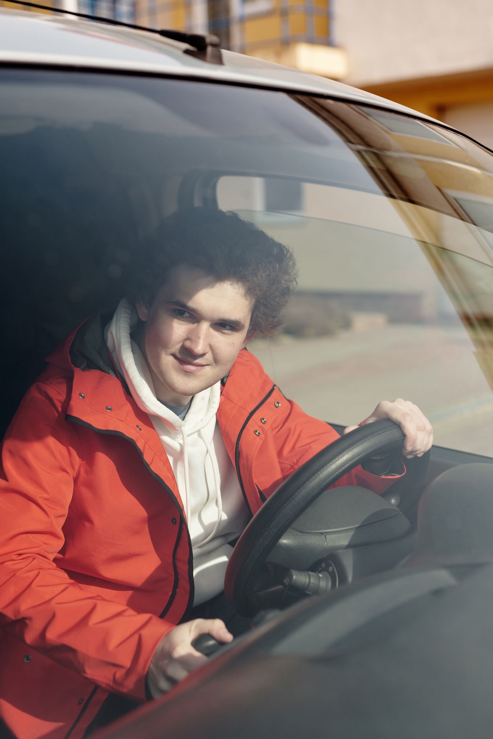 Jeune conducteur souriant au volant de sa première voiture